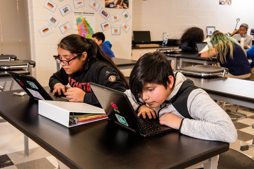 Two students use computers in a classroom.